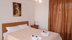 Una cama bien tendida con ropa de cama a rayas, una mesita de noche con lámpara y un cuadro en la pared.