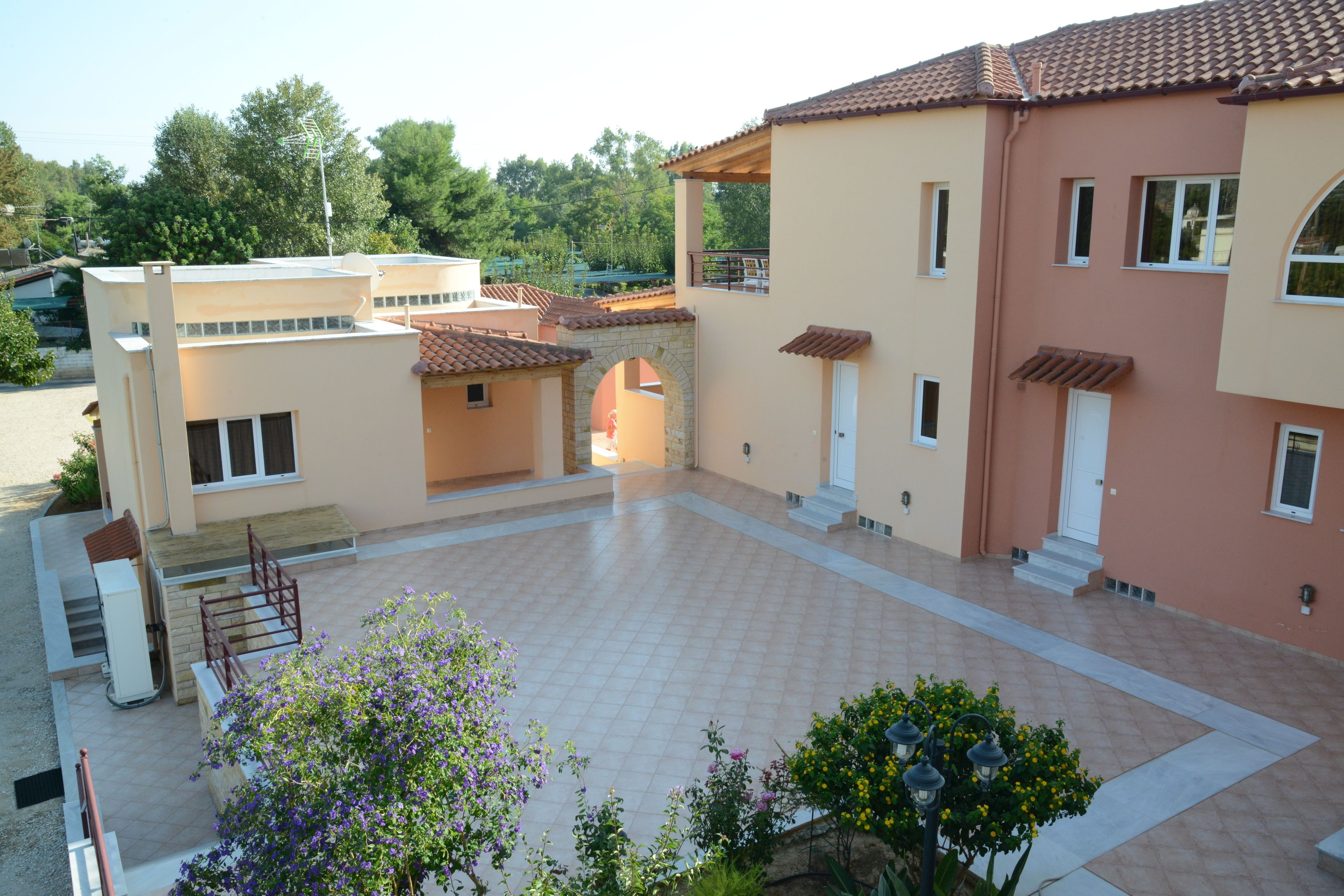 A two-story building with a courtyard, featuring a mix of modern and traditional architectural elements, including a stone archway and a tiled roof.