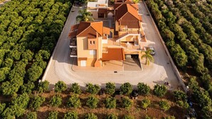 Una zona residencial costera con una casa destacada de techo de tejas, rodeada de abundante vegetación y una vista despejada al mar.
