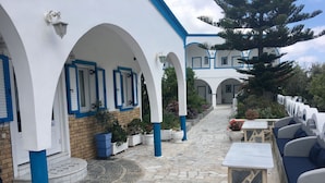 Un pati amb arquitectura blanca i blava, paviment de pedra i mobiliari exterior.
