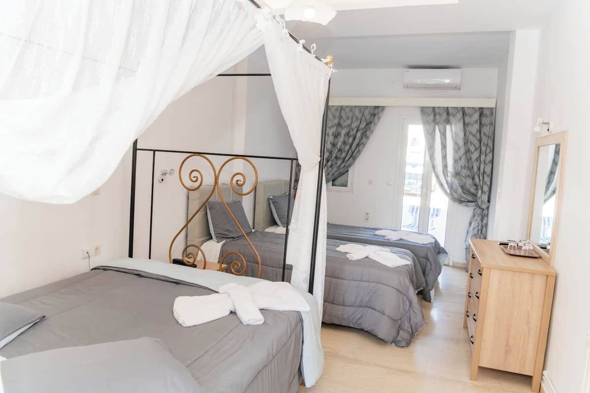 A bedroom with a canopy bed, a bedside table, a mirror, and a wardrobe.