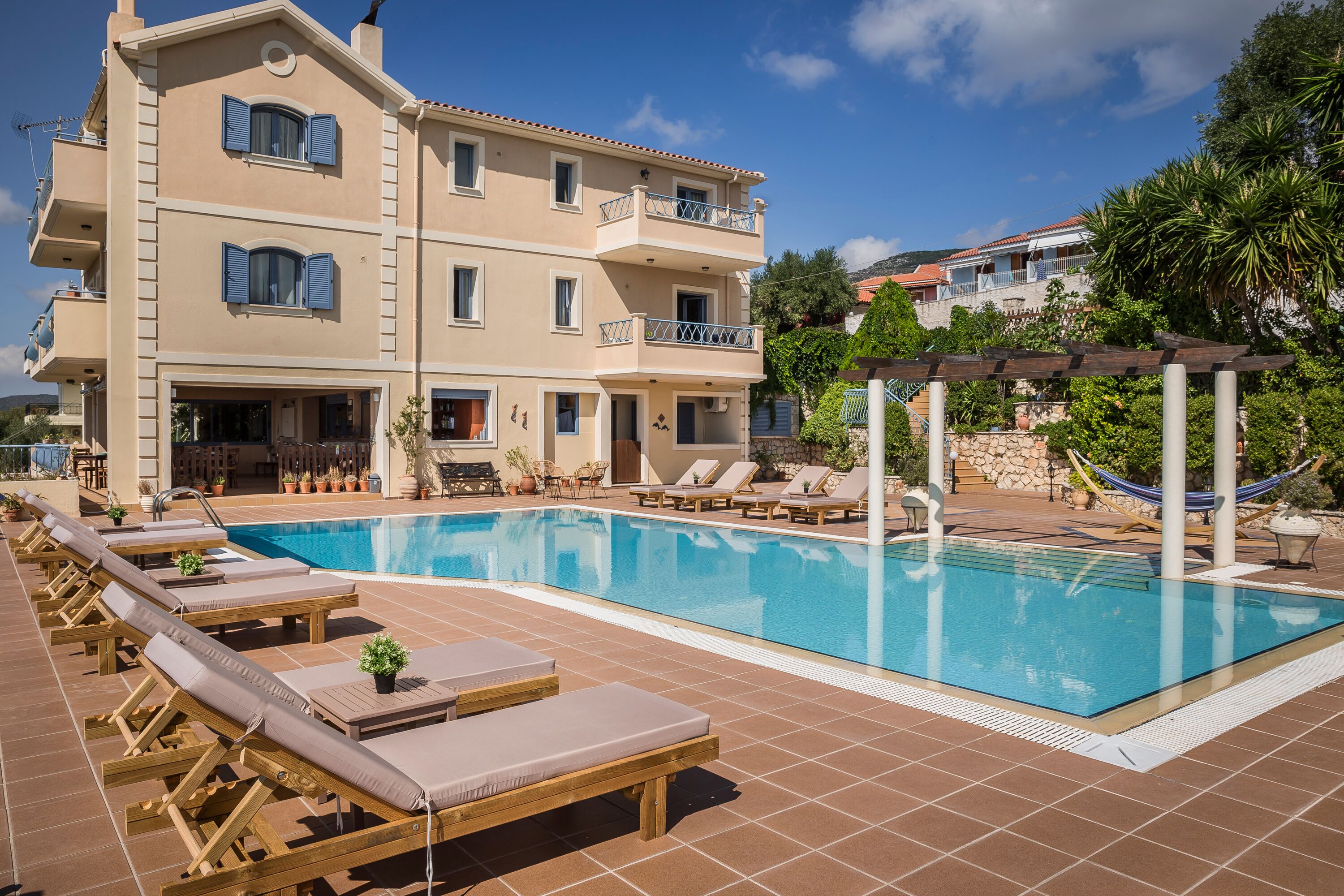 Un hôtel doté d’une piscine, de chaises longues et d’un espace abrité avec un hamac.