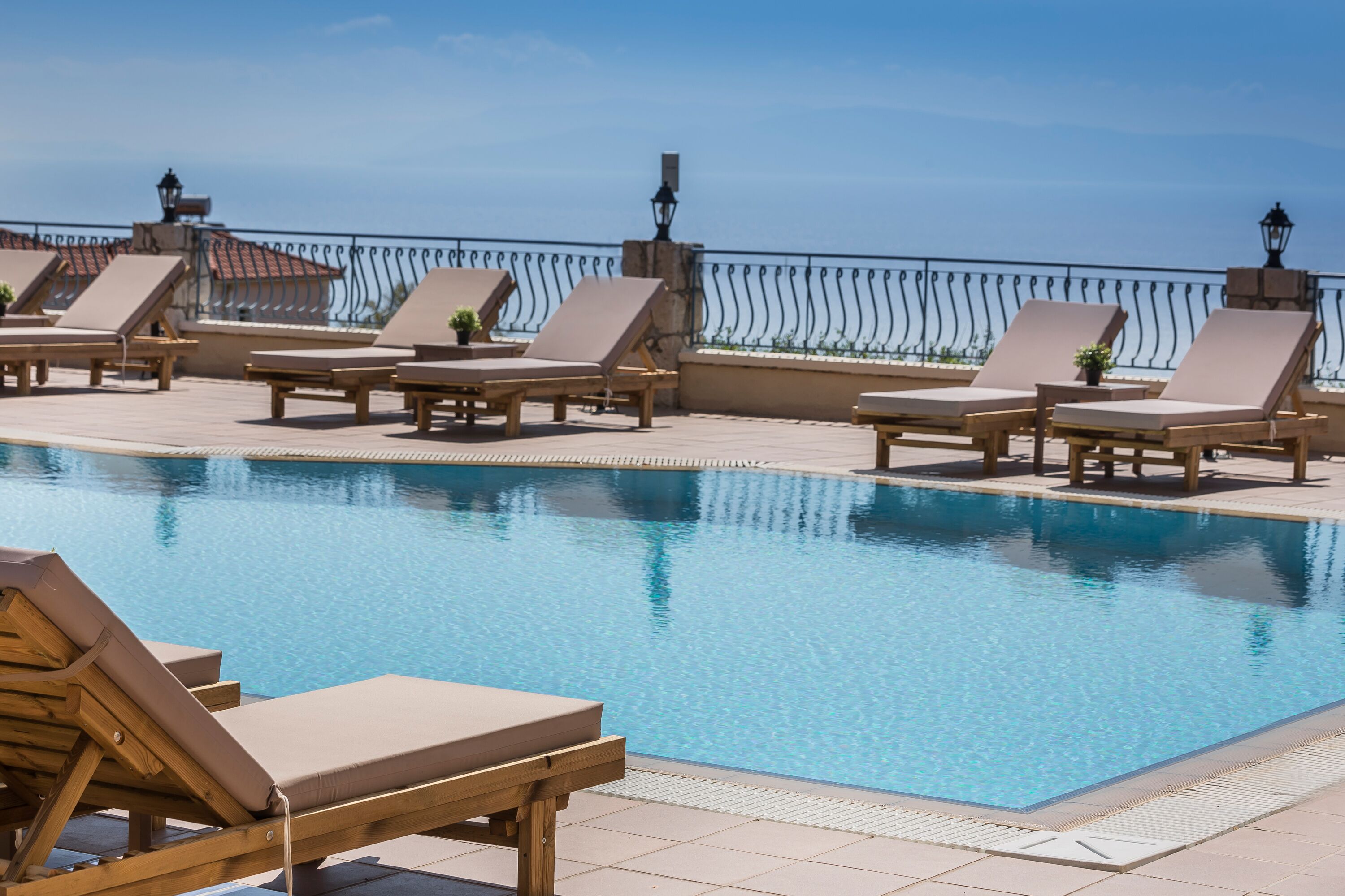 A poolside area with lounge chairs and a clear view of the sea.