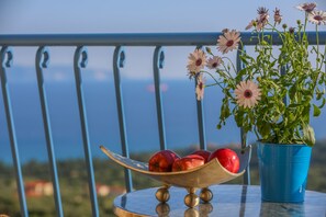 Uma mesa com uma tigela de metal contendo maçãs vermelhas e uma panela azul com flores.