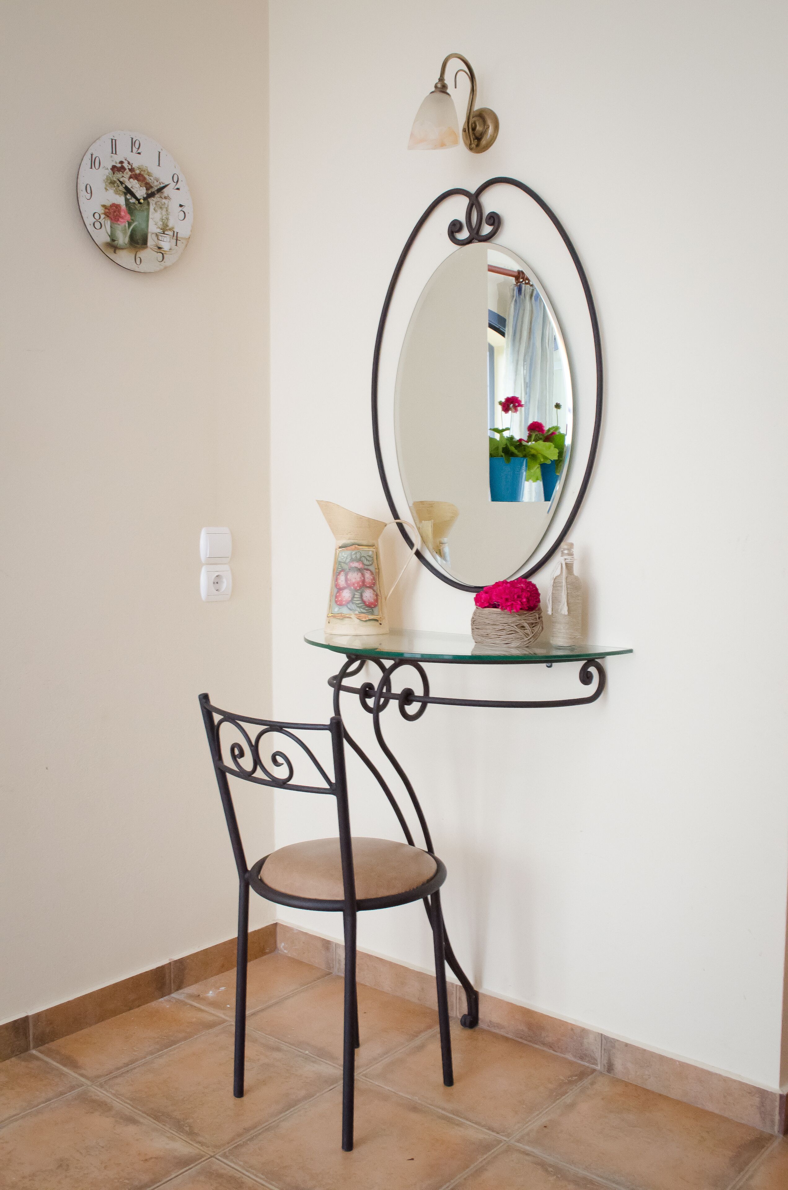 A small room with a round wall clock, a mirror, and a chair.