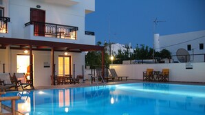 Una piscina con sillones de descanso y una zona de estar cubierta.