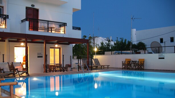 A swimming pool with lounge chairs and a covered seating area. - Iliovasilema (Naxos)