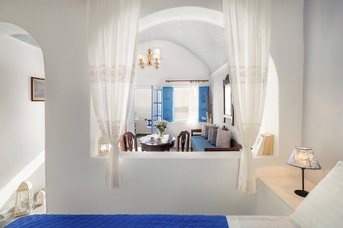 A bedroom with a bed, a nightstand, a lamp, and a window with curtains.