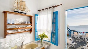 A bathroom with a ship model, a sink, and a window with blue shutters. - Annio Flats (Santorini)