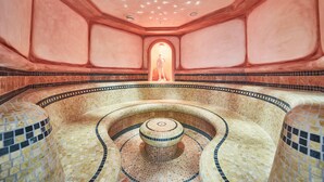 A circular, tiled pool area with a central fountain and a statue in the background. - Hotel Römerhof (Fusch an der Grossglocknerstrasse)