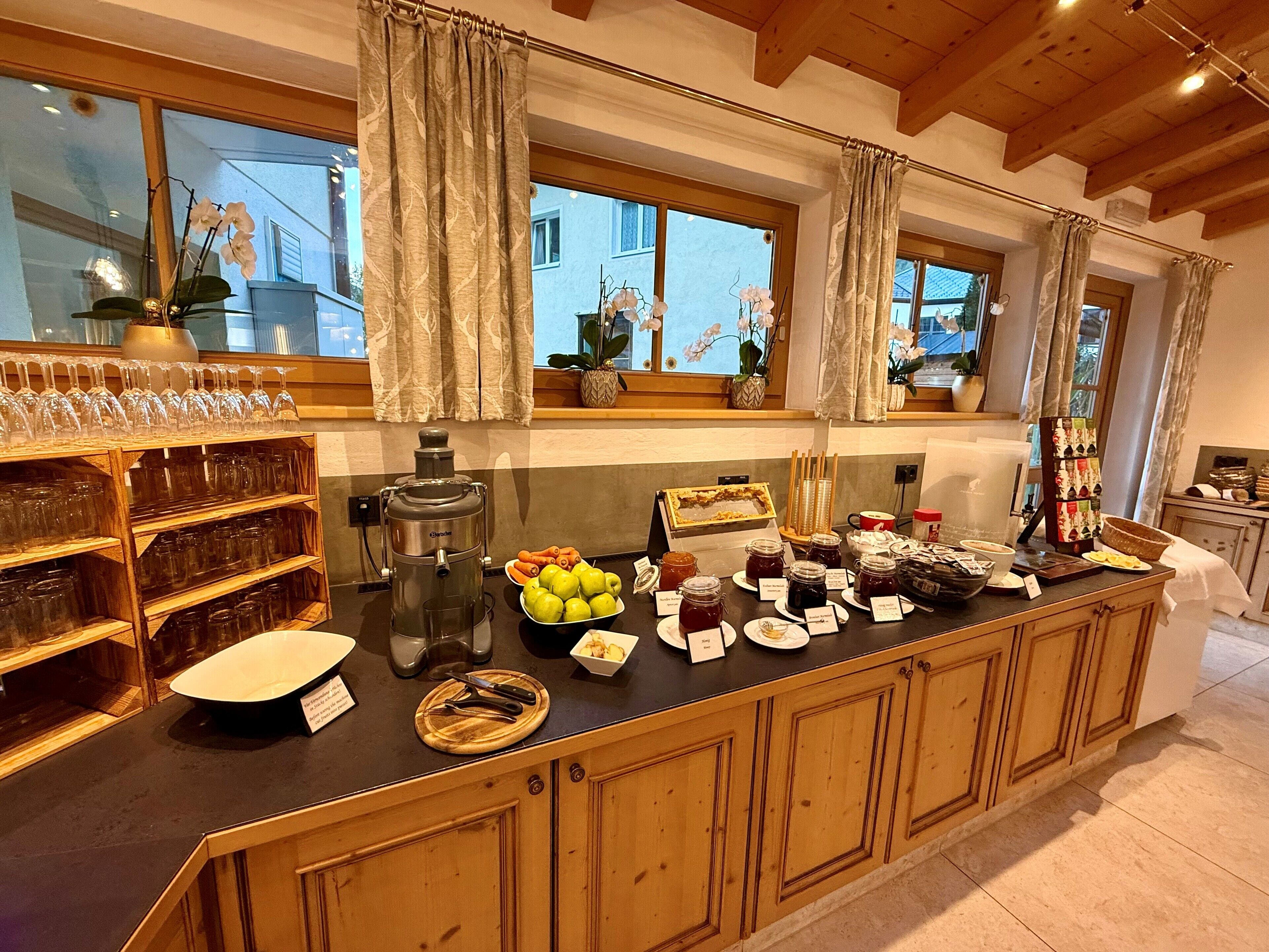 Un buffet pour le petit-déjeuner proposant divers aliments et accompagnements, une machine à café et une sélection de verres à vin.