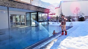 Una piscina techada, una piscina al aire libre, sombrillas