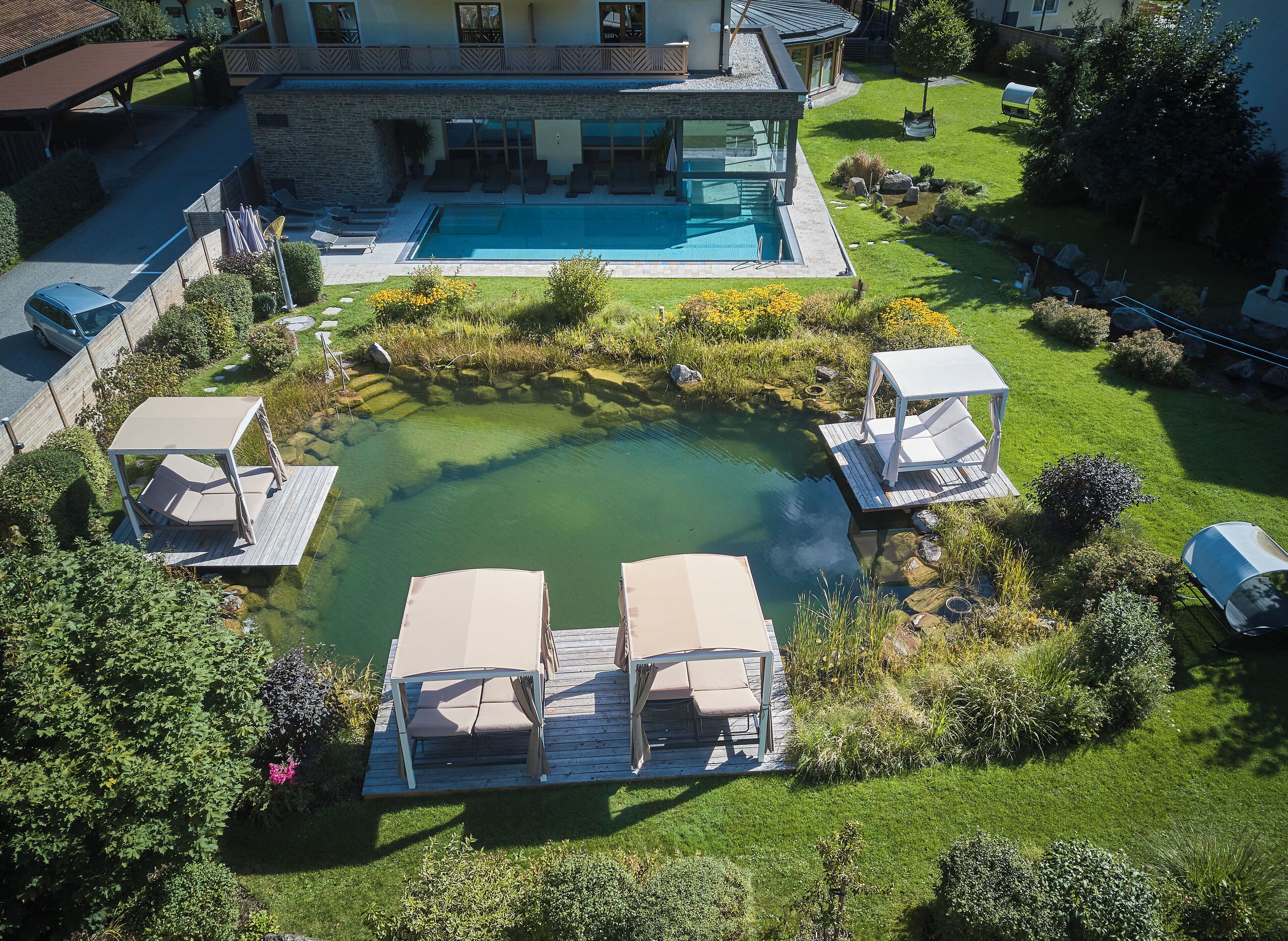 Vue aérienne d’une propriété résidentielle dotée d’une piscine, de chaises longues et d’un jardin bien entretenu.