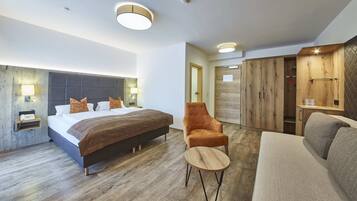Habitación de hotel moderna con una cama grande, un armario de madera, una mesita redonda pequeña y un sofá.