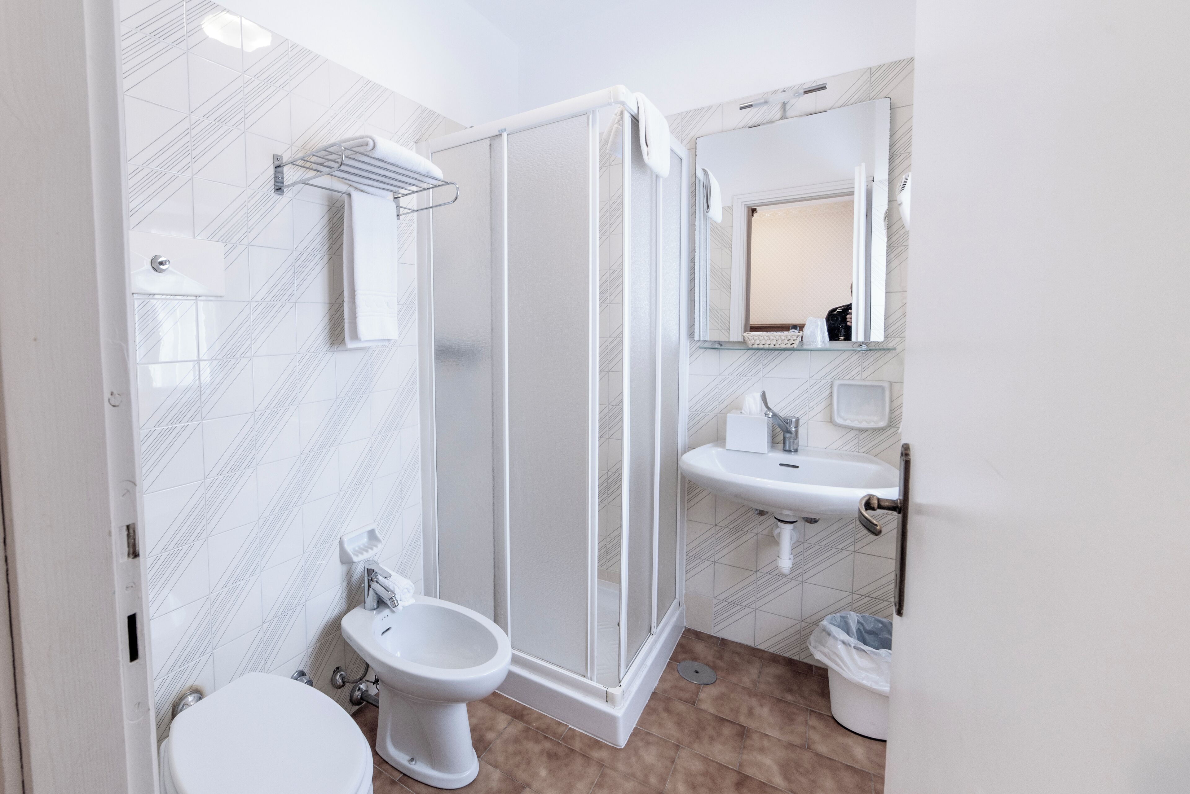 Une salle de bain équipée d’une douche, de toilettes, d’un lavabo et d’un miroir.