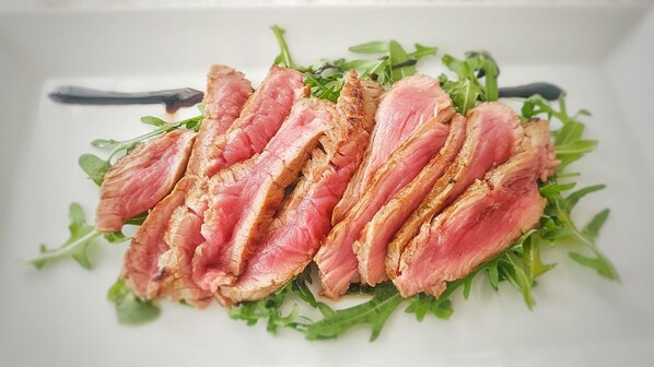A white plate with sliced meat and greens.