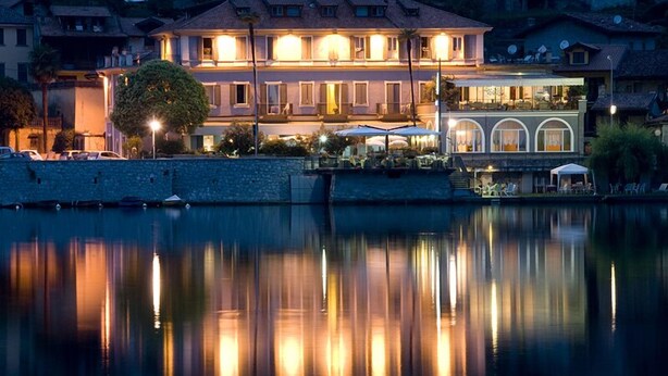 Un hotel frente al agua con su reflejo en el agua, que cuenta con un edificio grande con varios balcones y zonas de estar al aire libre.