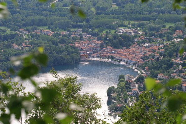 A riverside town with red-roofed buildings, a bridge, and lush greenery.
