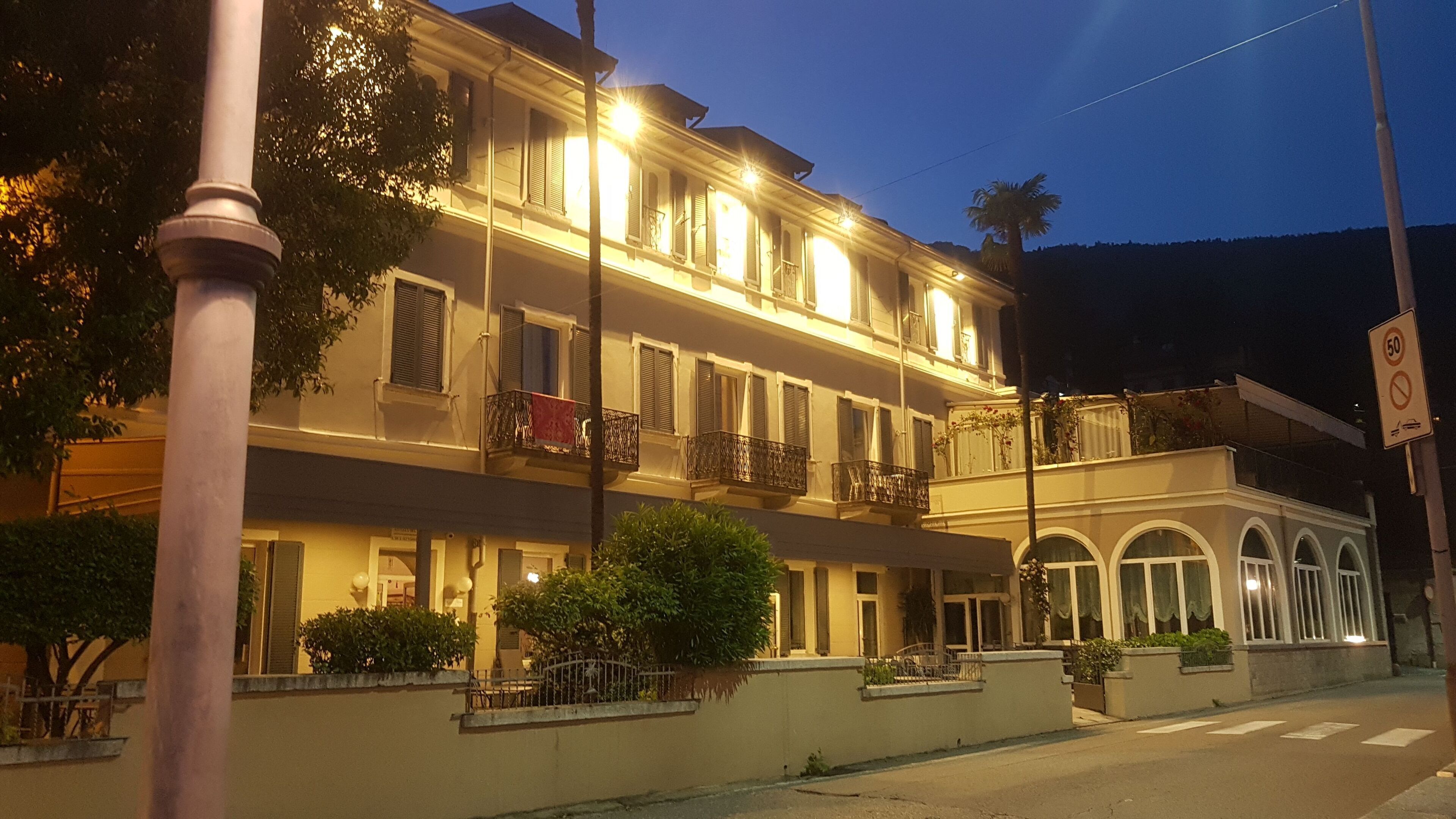 A multi-story hotel with balconies, a street view, and a 50 km/h speed limit sign.