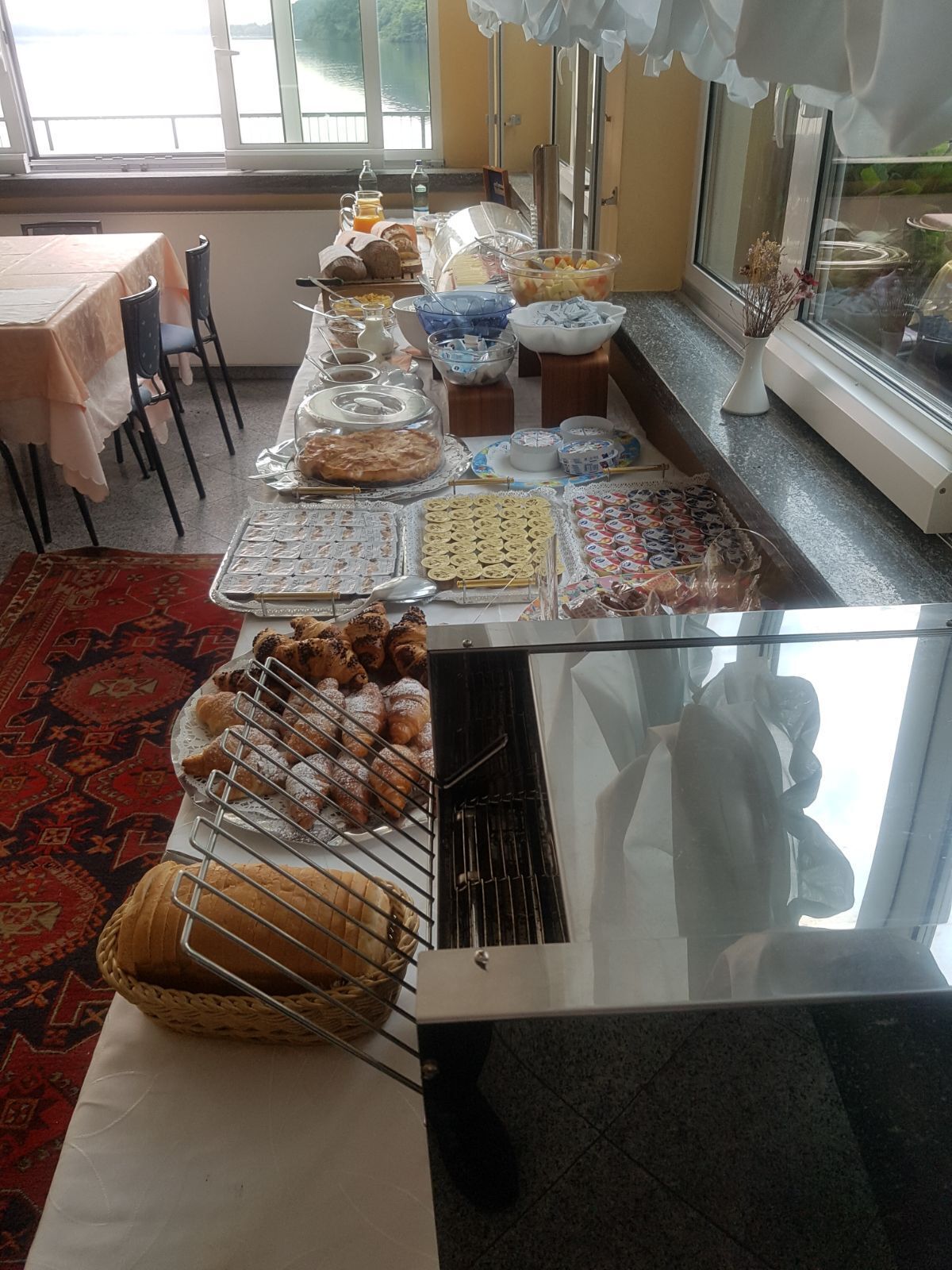 A buffet table with various food items, including pastries, bread, and a grill.