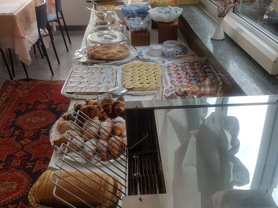 A buffet table with various food items, including pastries, bread, and a grill.