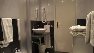 Un baño moderno con un espejo grande, un lavamanos blanco y un perchero para toallas.