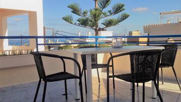A terrace with a table and chairs, a potted tree, and a railing.