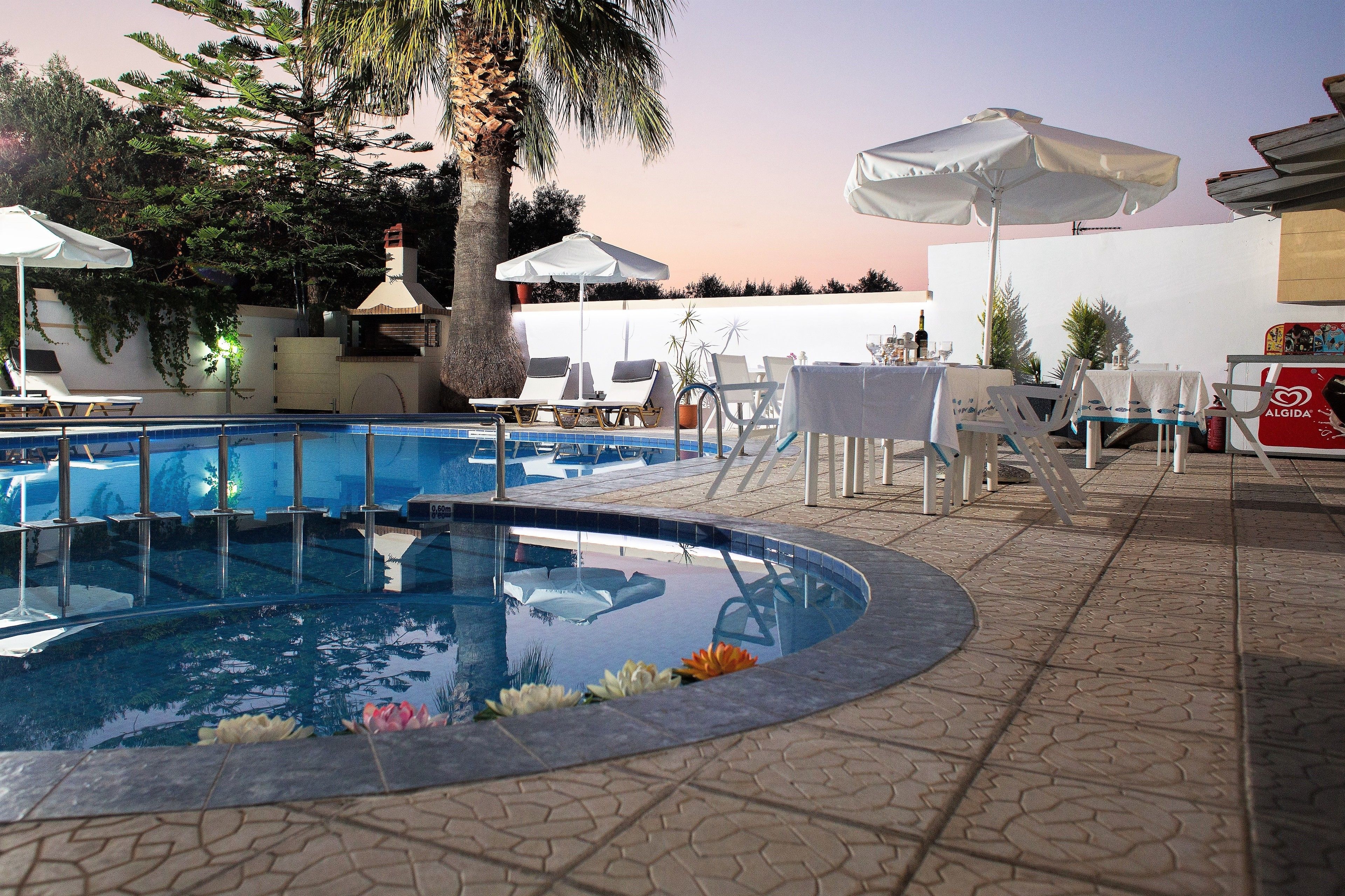 A pool area with lounge chairs, umbrellas, and a tiled deck.