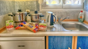 Una cocina con estufa, ollas, hervidor y varios alimentos sobre la encimera.