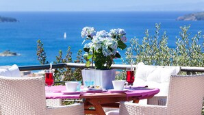 A table set with white cups, a pink tablecloth, and a vase of flowers. - Vigles Sea View (Skiathos)