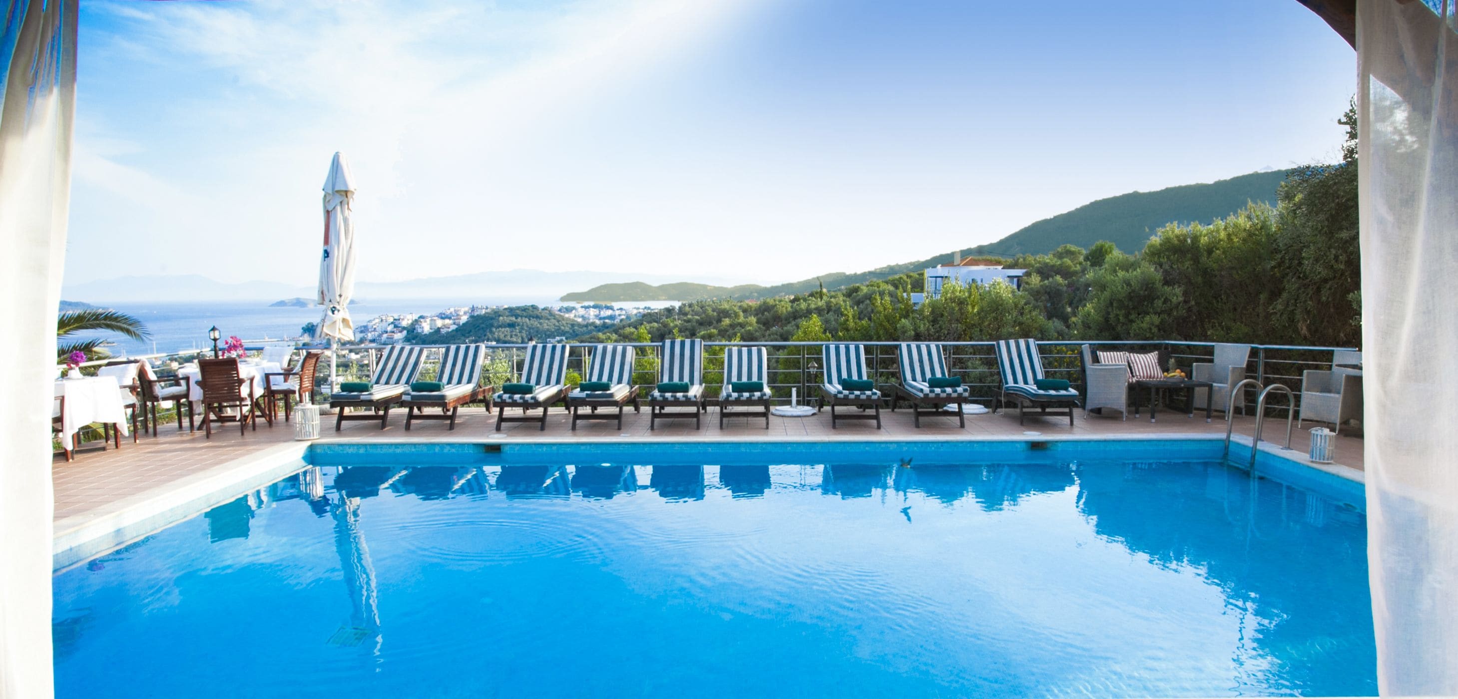 Una piscina al aire libre, sombrillas, sillones reclinables de piscina