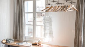 Una habitación con un ventanal grande, un aparador de madera, un sombrero y una percha para colgar ropa.