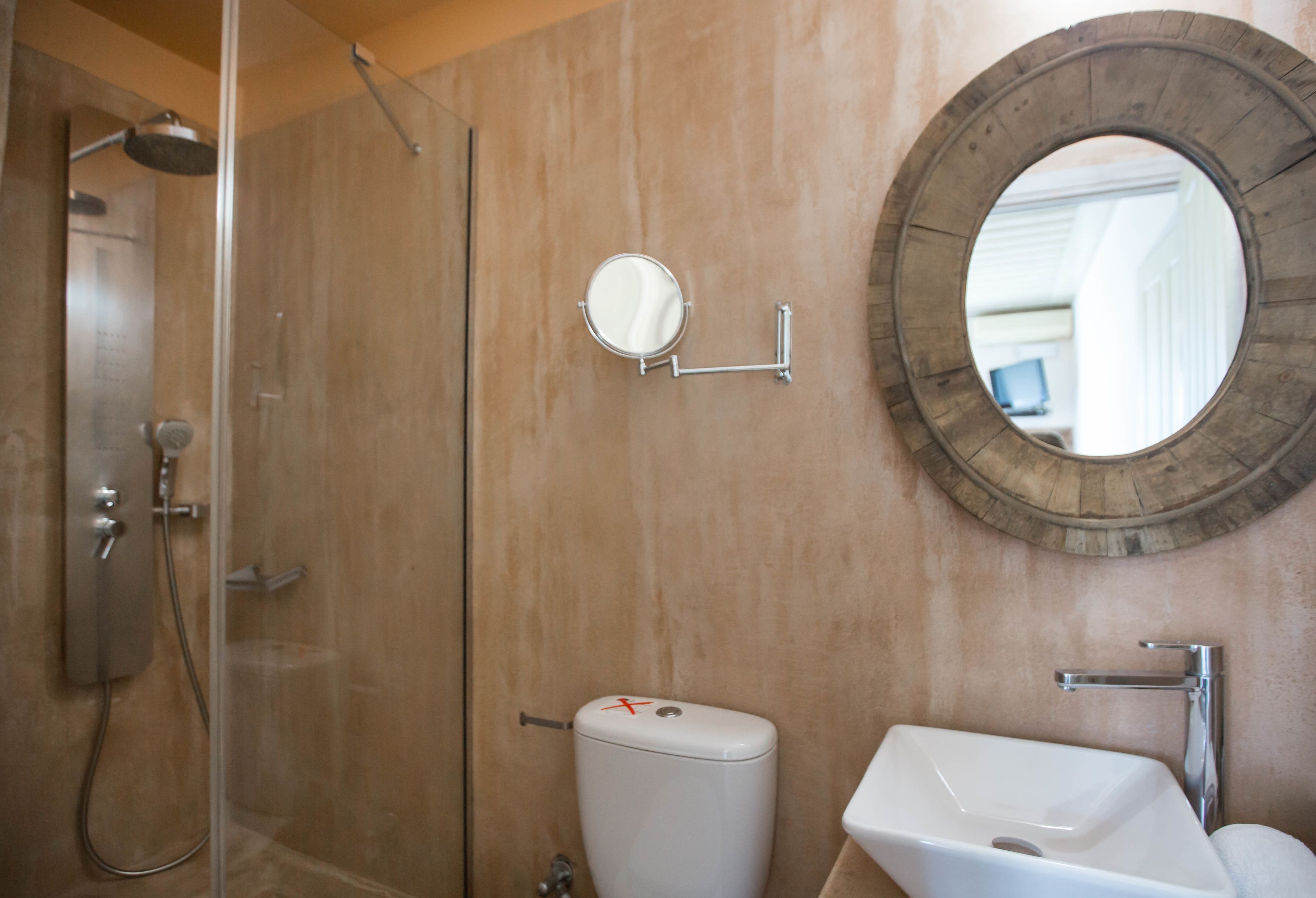 A bathroom with a shower, toilet, sink, and two mirrors.