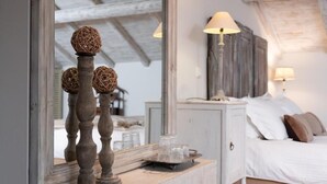 Un dormitorio con cama, lámparas de noche, cómoda y espejo que refleja la habitación.