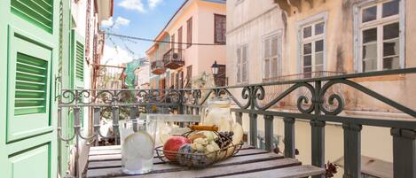 A balcony with a table holding a basket of fruits and a pitcher of iced tea.