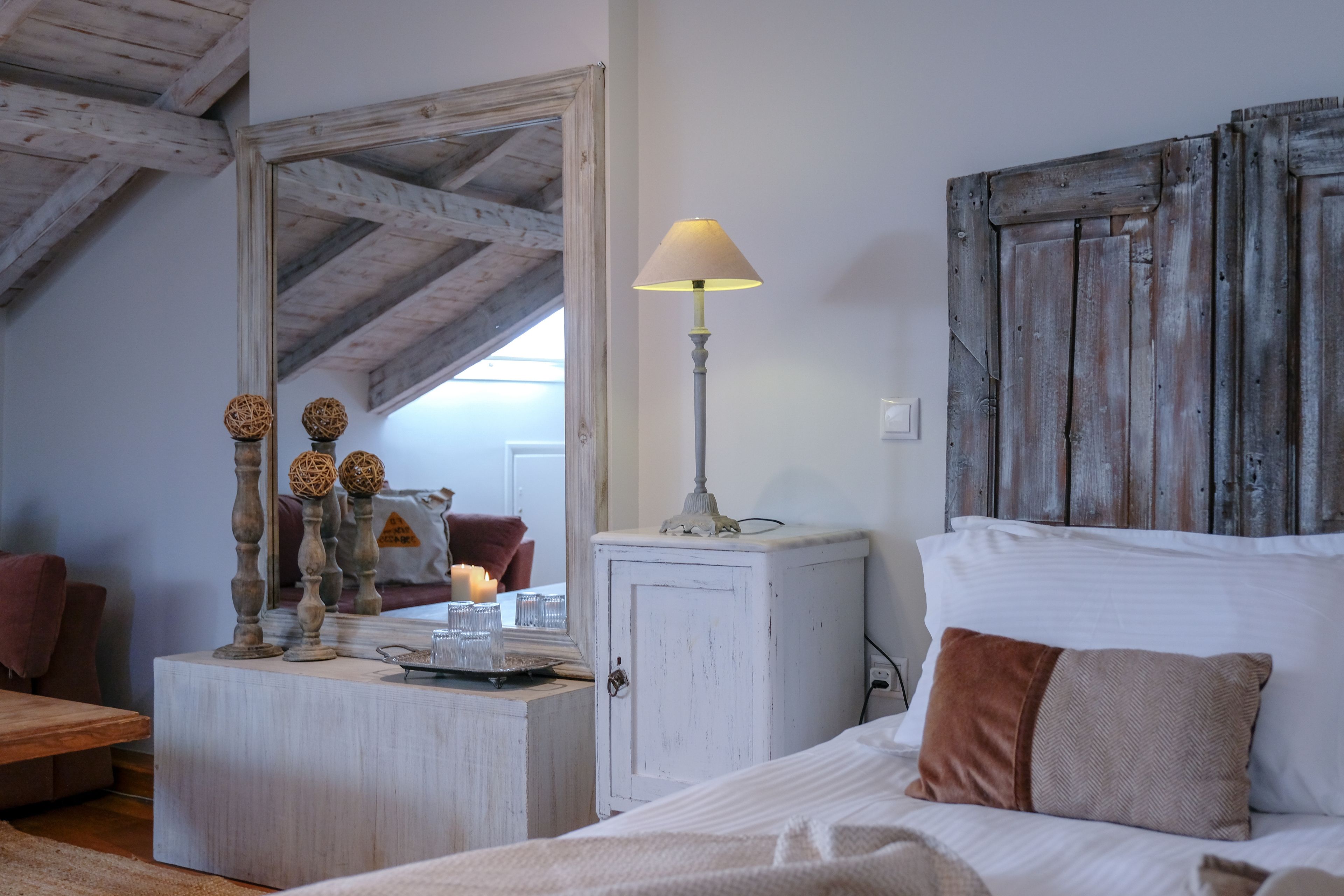 A bedroom with a bed, a bedside table with a lamp, a wardrobe, and a mirror.