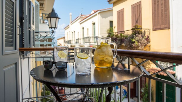 Una mesa con una jarrón, vasos y un par de gafas de sol en un balcón.