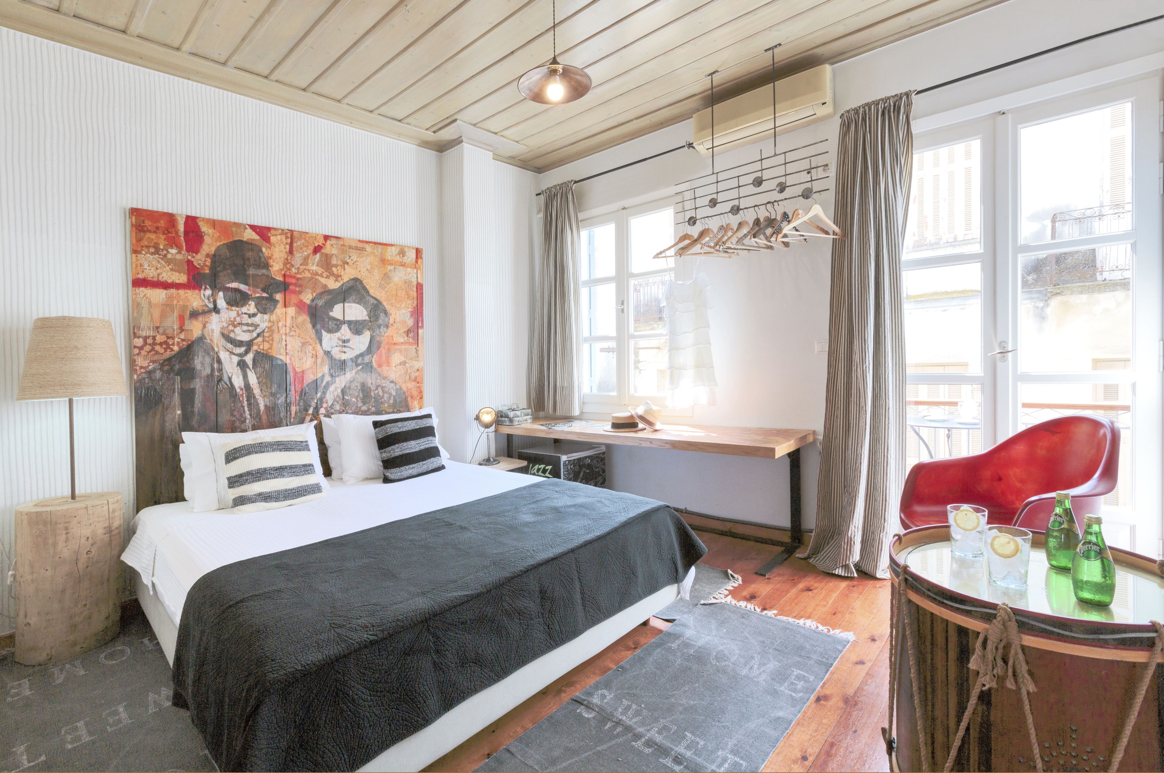 Una camera da letto con un letto, una scrivania, una sedia, un tavolo con delle bottiglie e un grande quadro appeso alla parete.