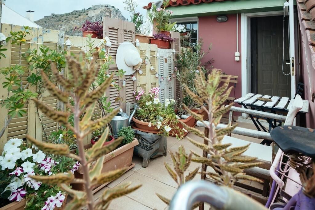 Ein kleiner Patio-Bereich mit Topfpflanzen, einem Fahrrad und einem Holzzaun.