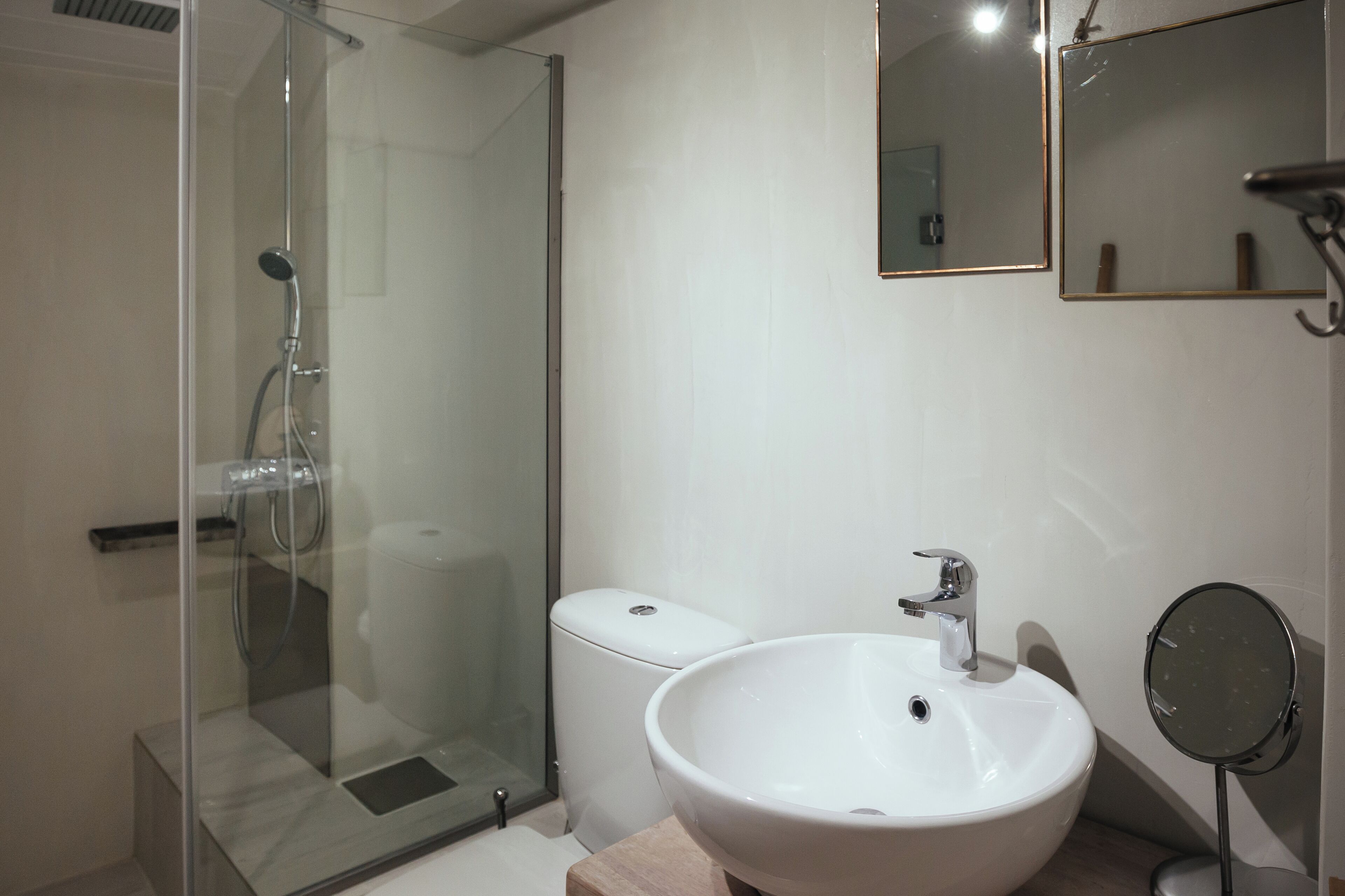 A bathroom with a glass-enclosed shower, a white sink, and a mirror.