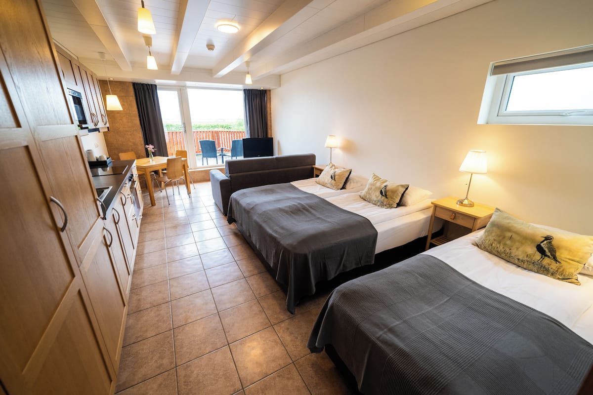 Ein Hotelzimmer mit zwei Betten, einem kleinen Schreibtisch, einem Fernseher und einem Balkon mit Blick.