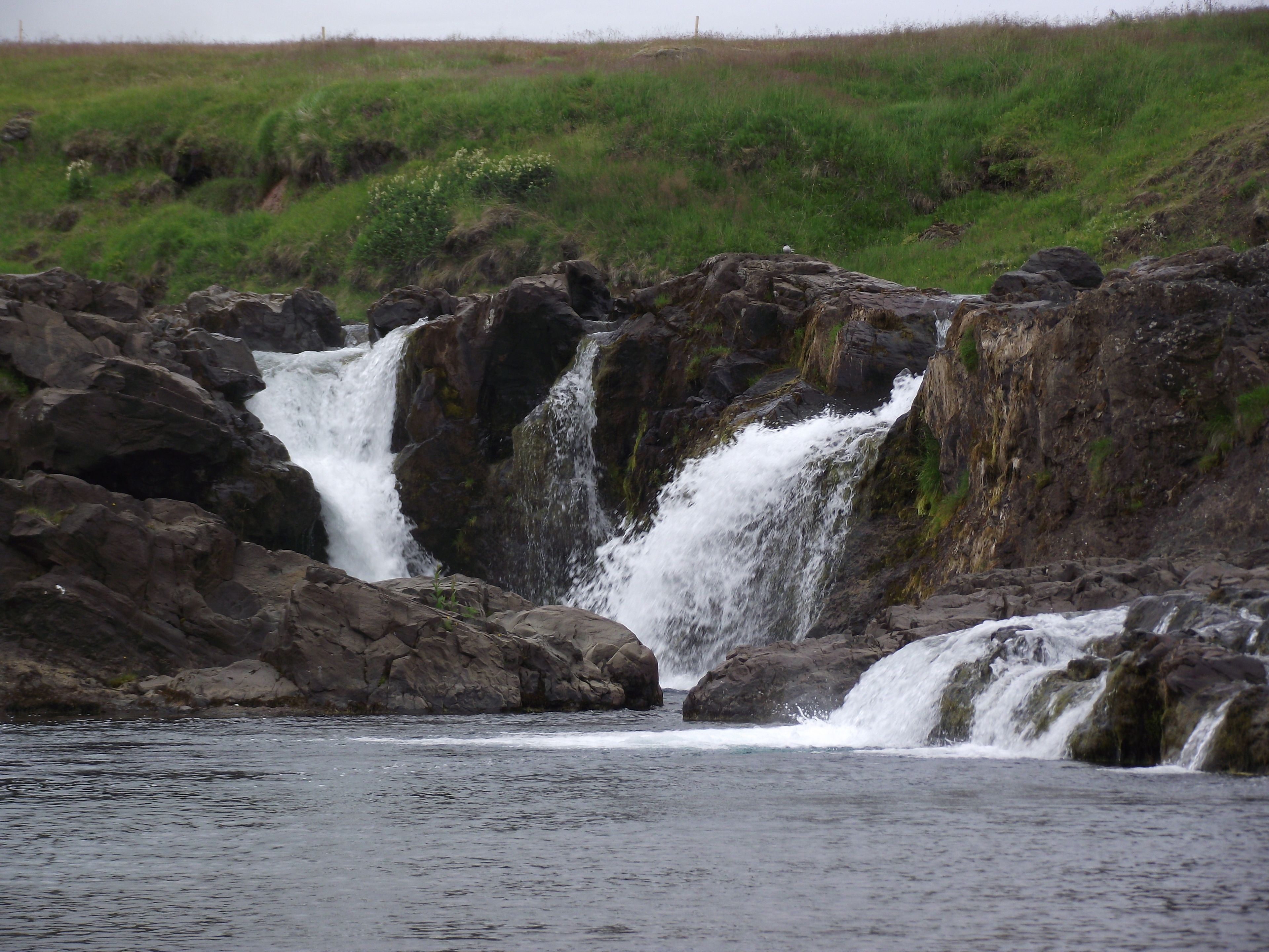 Een waterval die over rotsen in een watermassa stort.