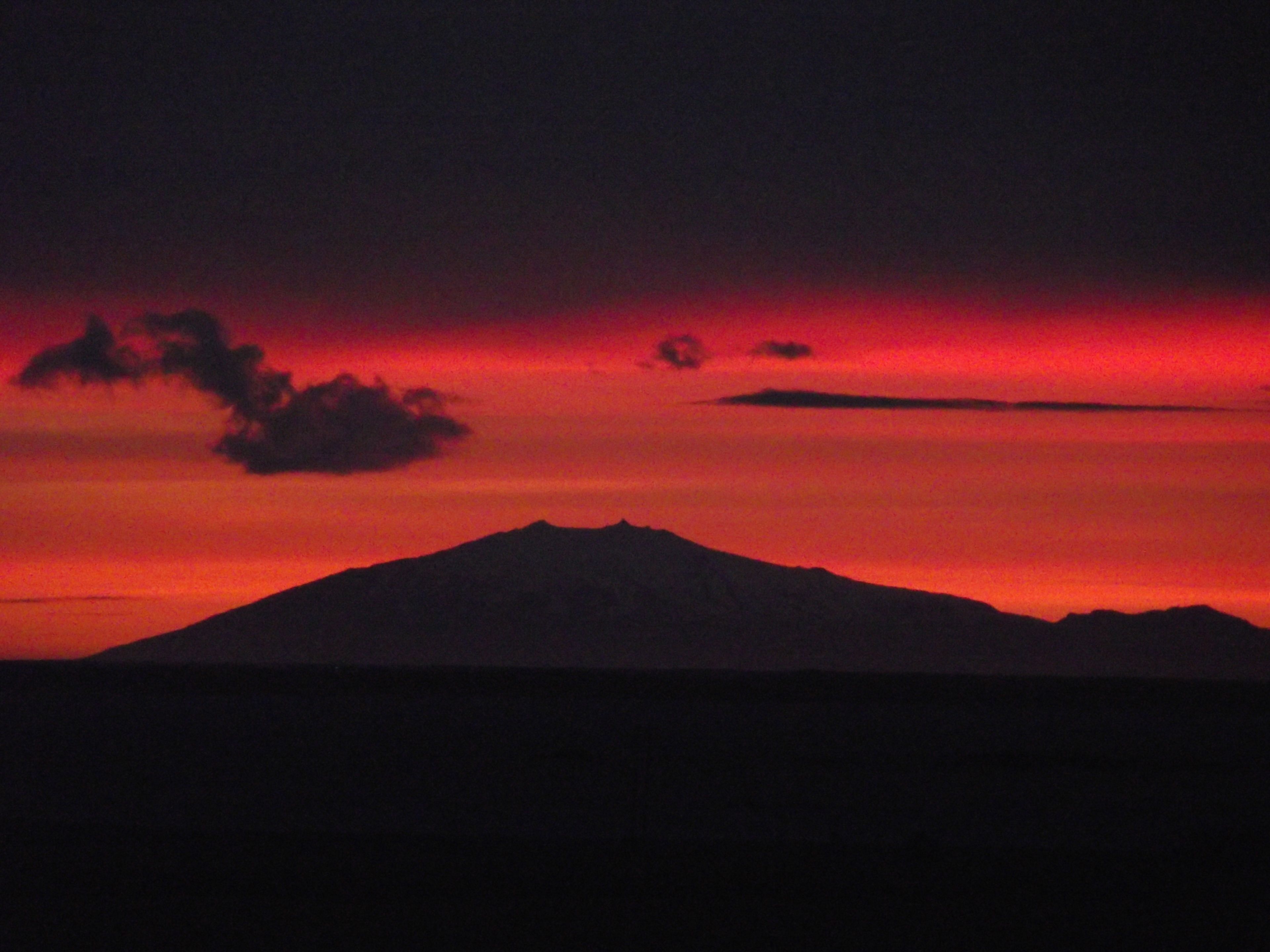 La silhouette d’une montagne se détachant sur un ciel rouge.