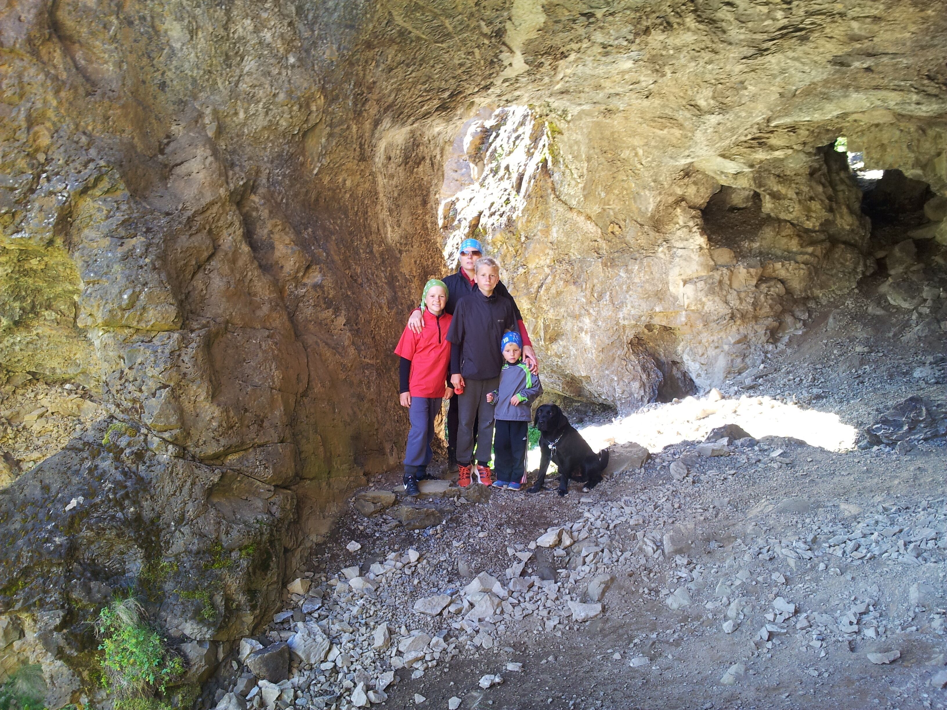 A group of people standing in a rocky cave with a dog.