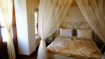 A bed with a metal frame and white bedding, a window with curtains, and a radiator in the corner.