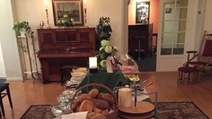 Una mesa de comedor con pan, un cuchillo y una copa de vino, rodeada de sillas y una alfombra estampada.