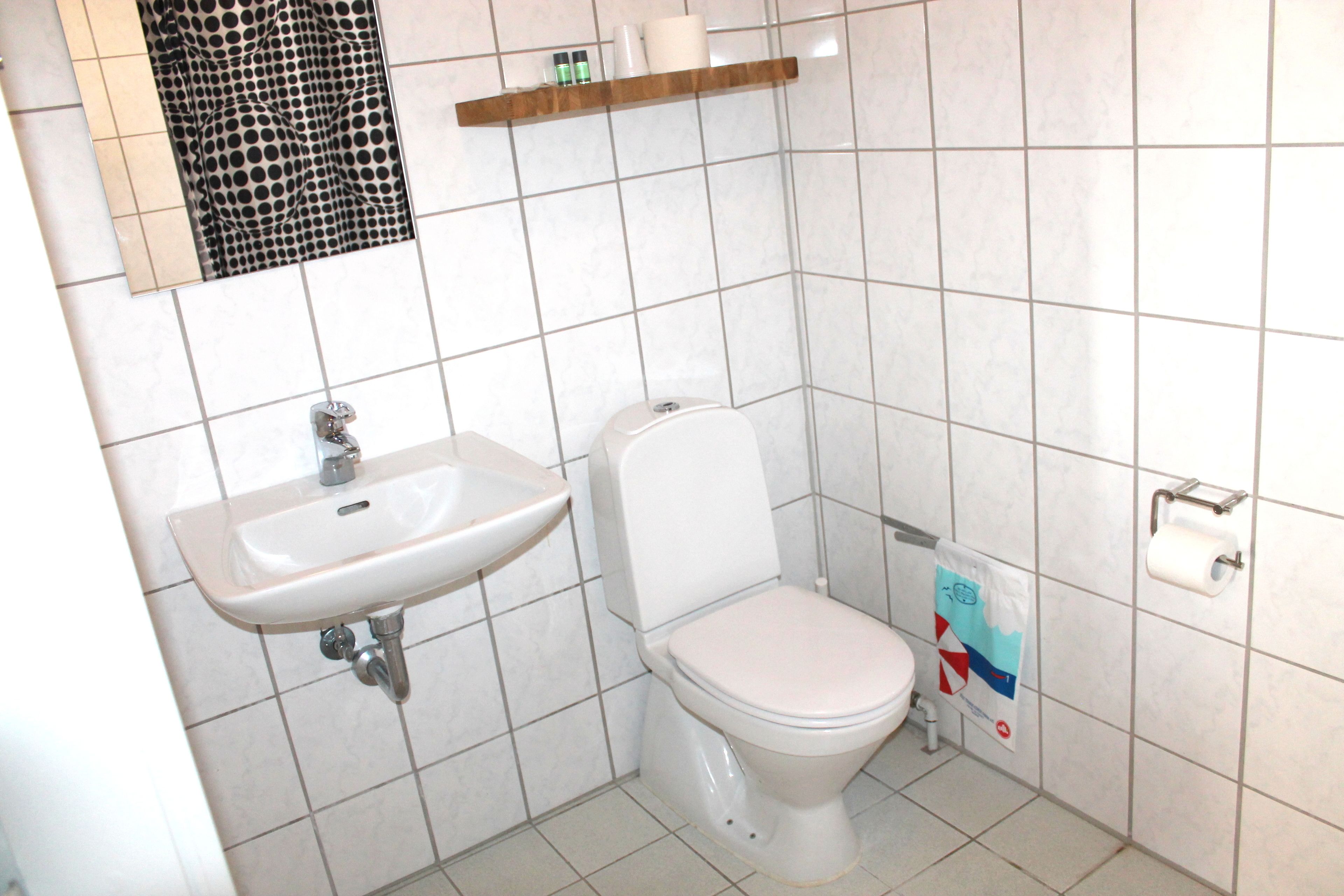 A bathroom with a white sink, toilet, and tiled walls.