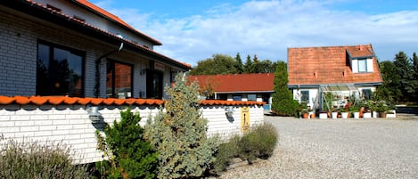 A building with a red-tiled roof, white brick exterior, and a gravel driveway.