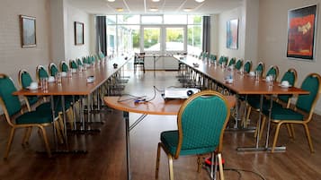 A conference room with long tables and chairs, large windows, and artwork on the walls.