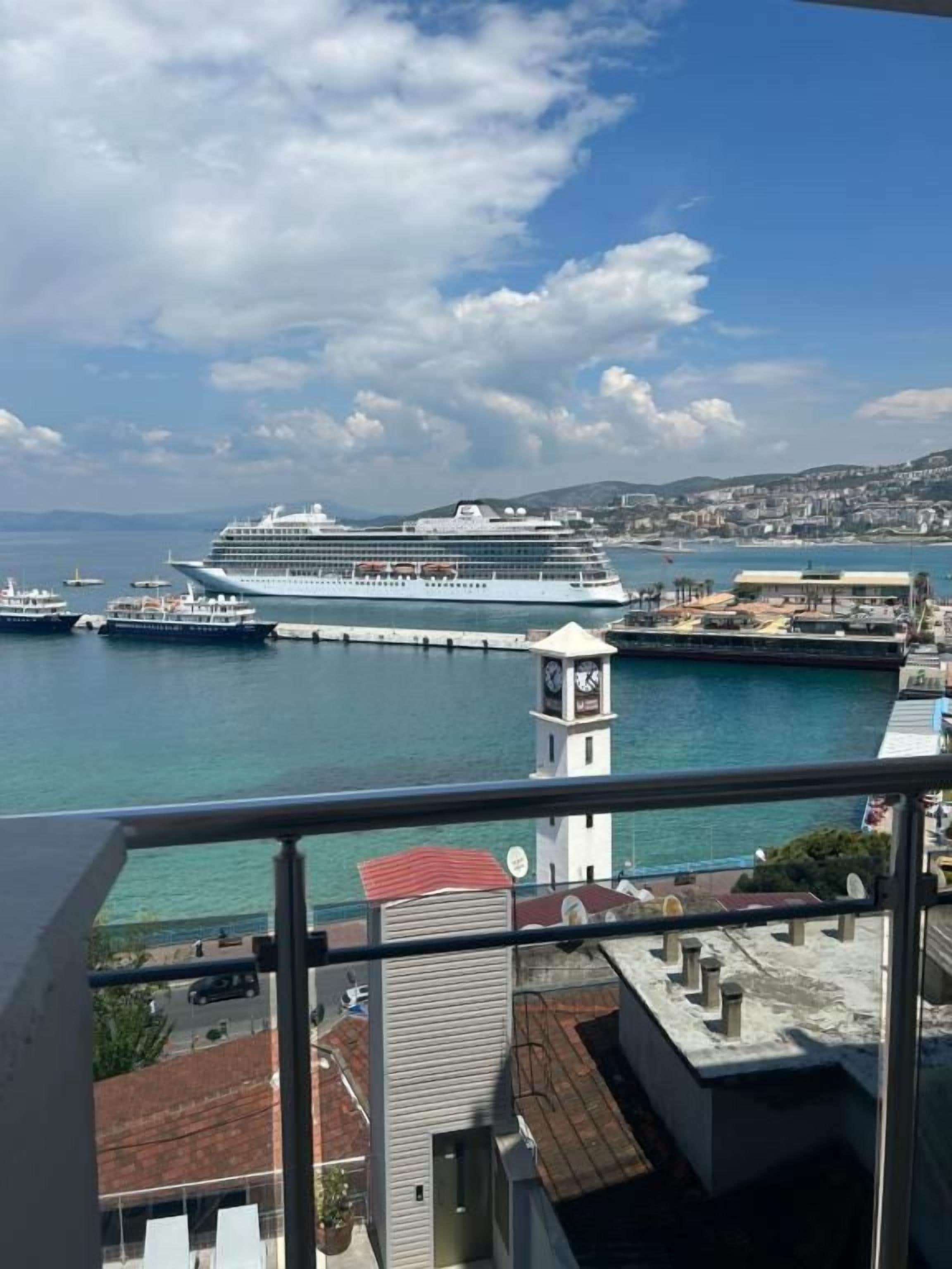 A cruise ship docked at a port with a clear view of the surrounding cityscape and water.